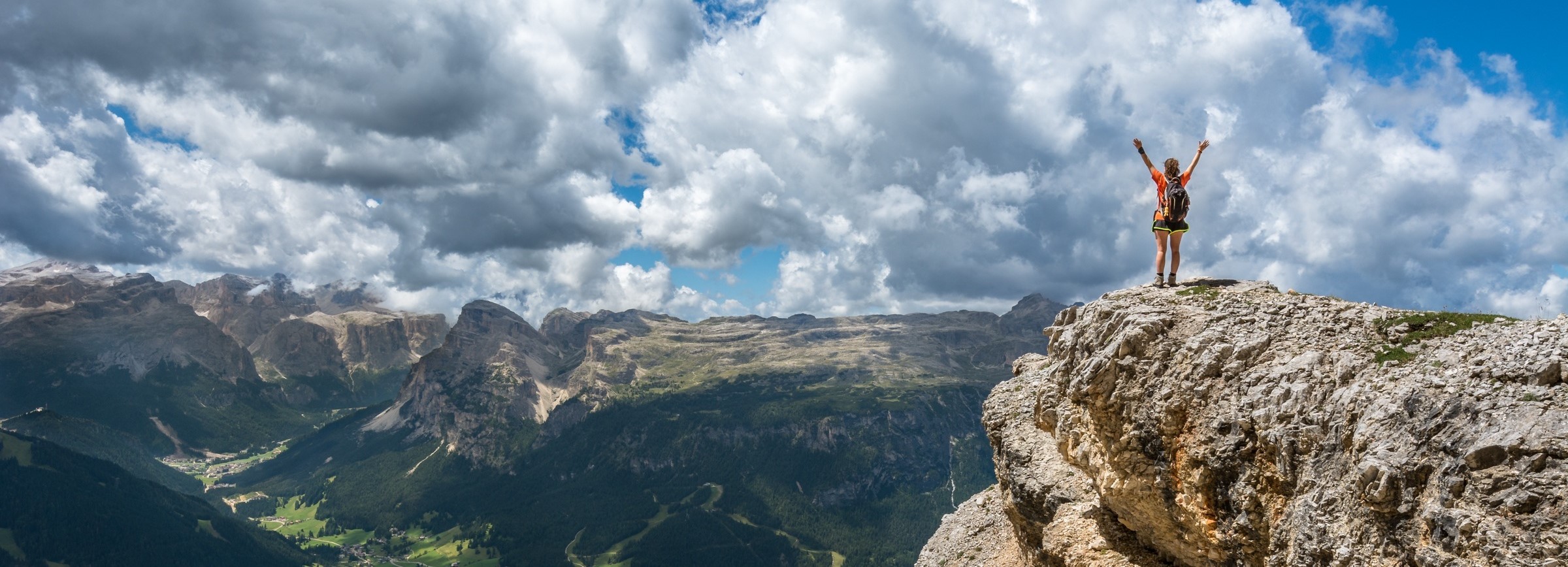 Woman at the top of a steep mountain celebrating her successful completion of a difficult hike