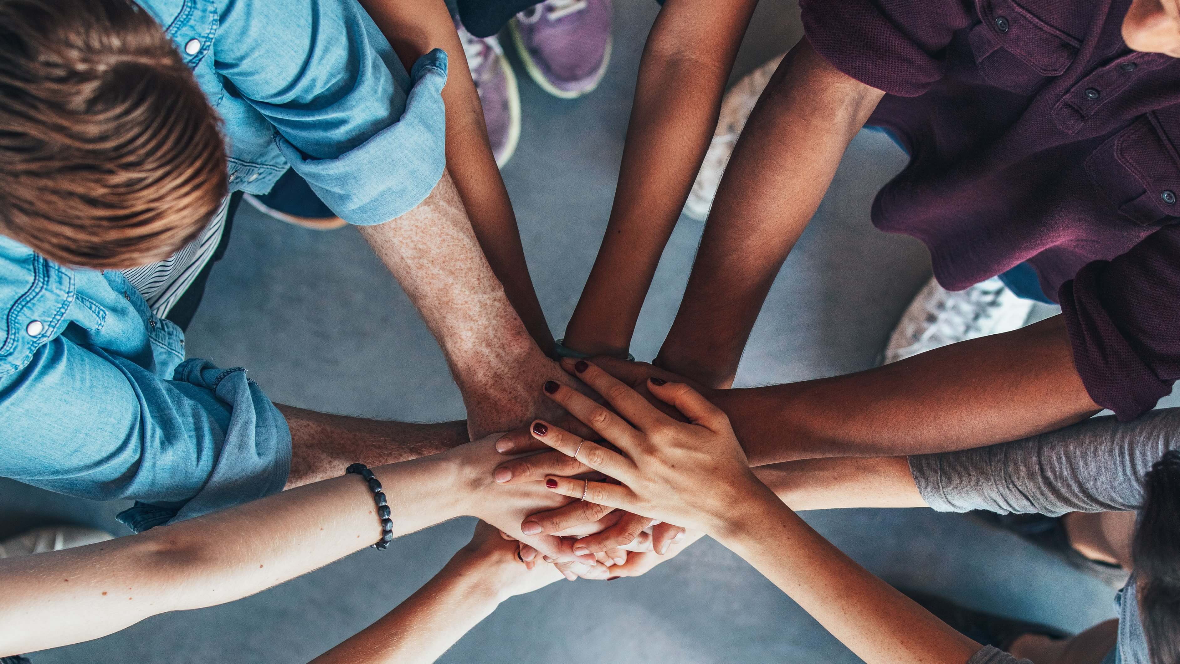 Team in a huddle with their hands in to signify unity