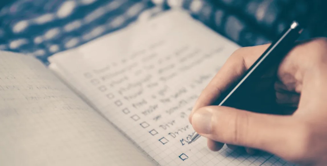 person's hand writing a checklist