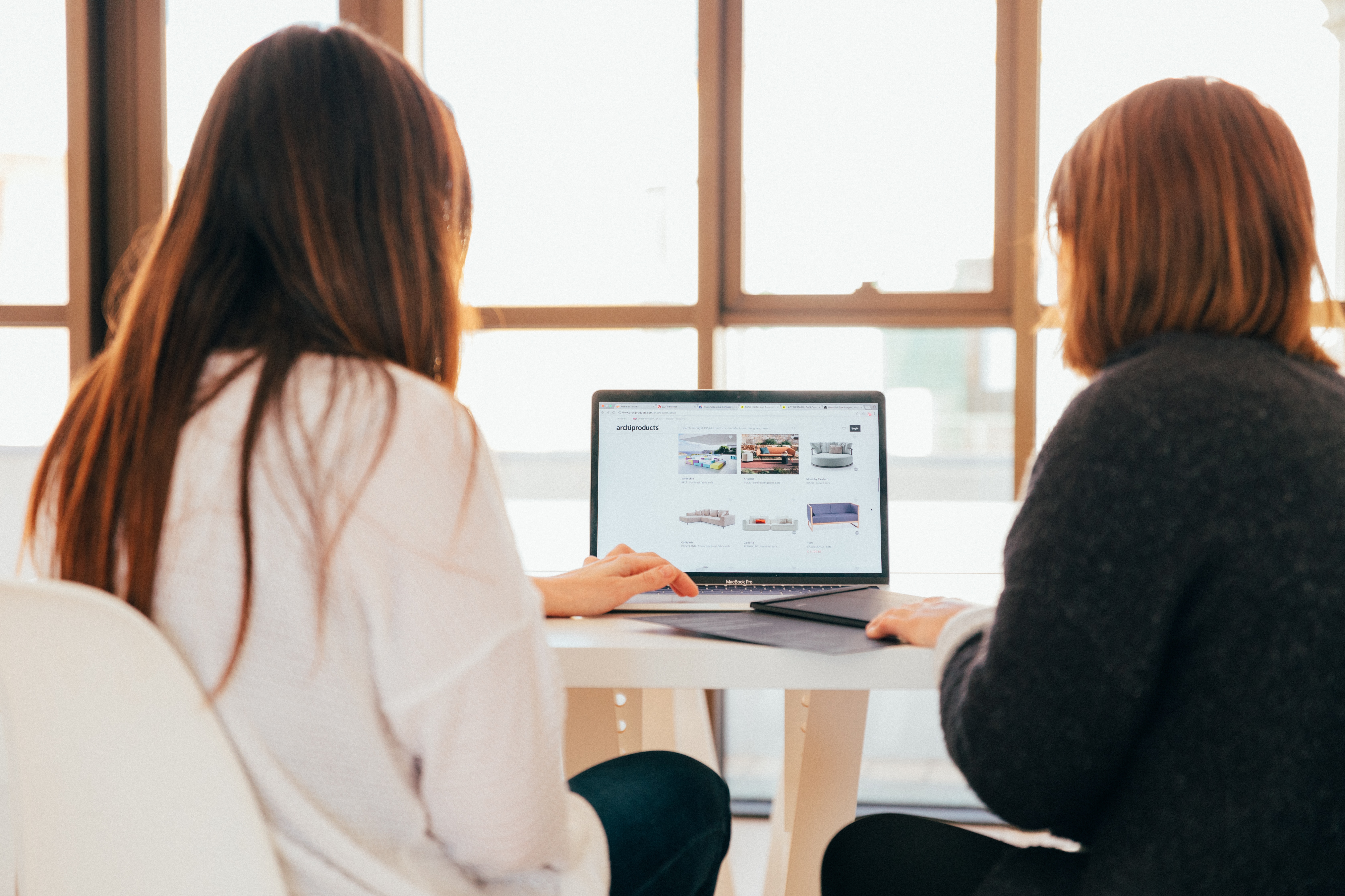 Two women talking while looking at laptop computer