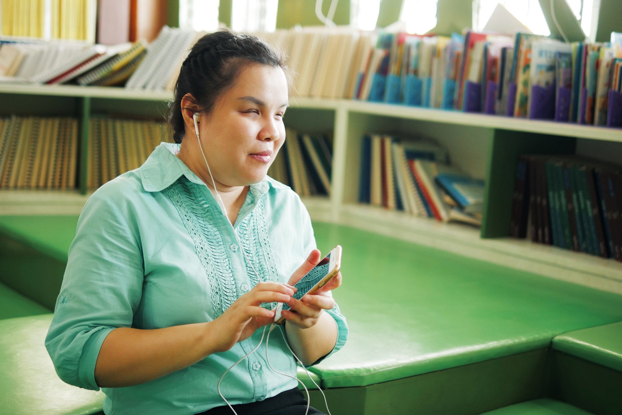 woman with blindness with headphones using smart phone with voice assistive technology in creative workplace library