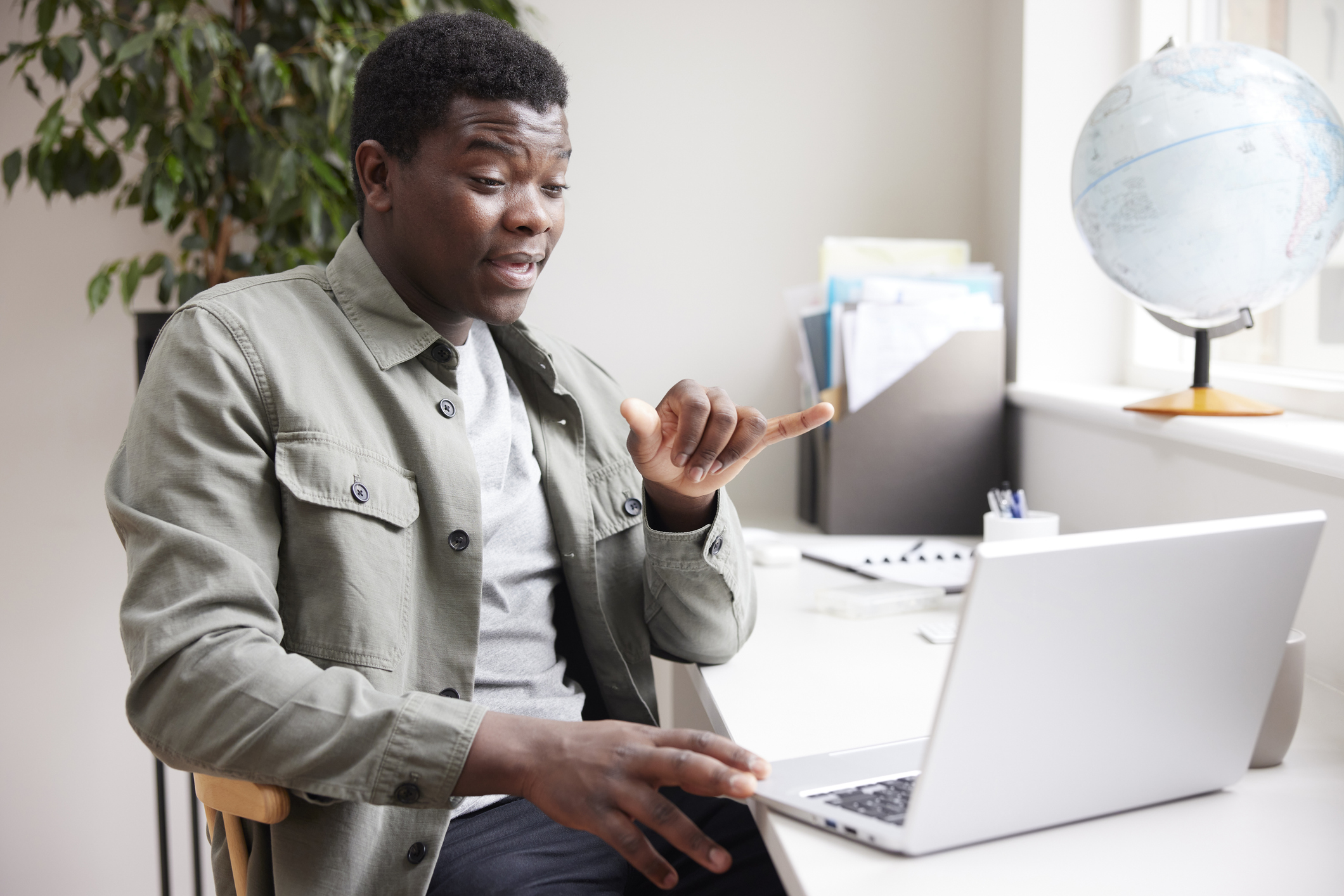 Young Man Having a Conversation Using Sign Language On Laptop At Home