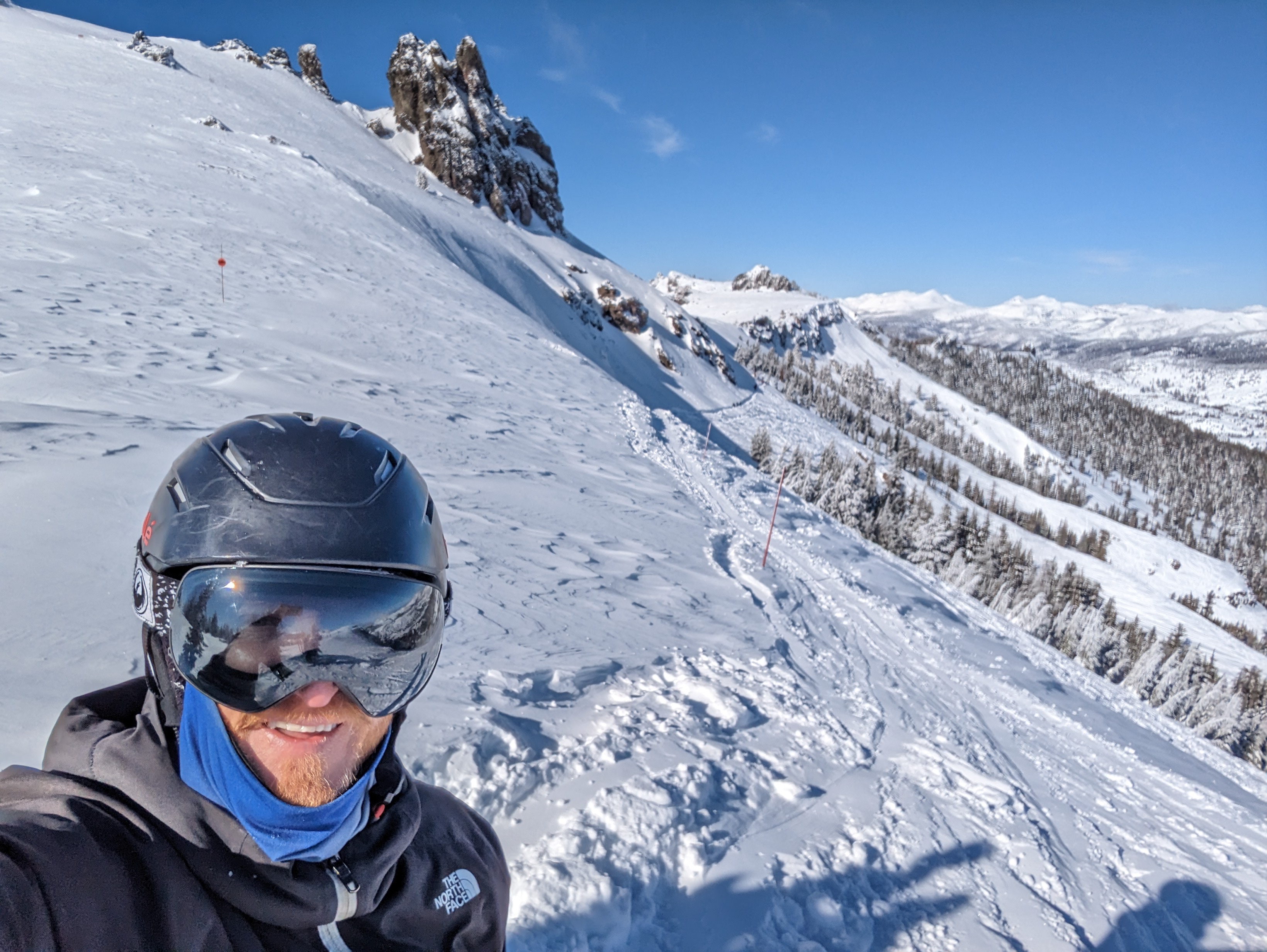 Brian Stafford in ski gear on the side of a mountain with a mountain range in the background