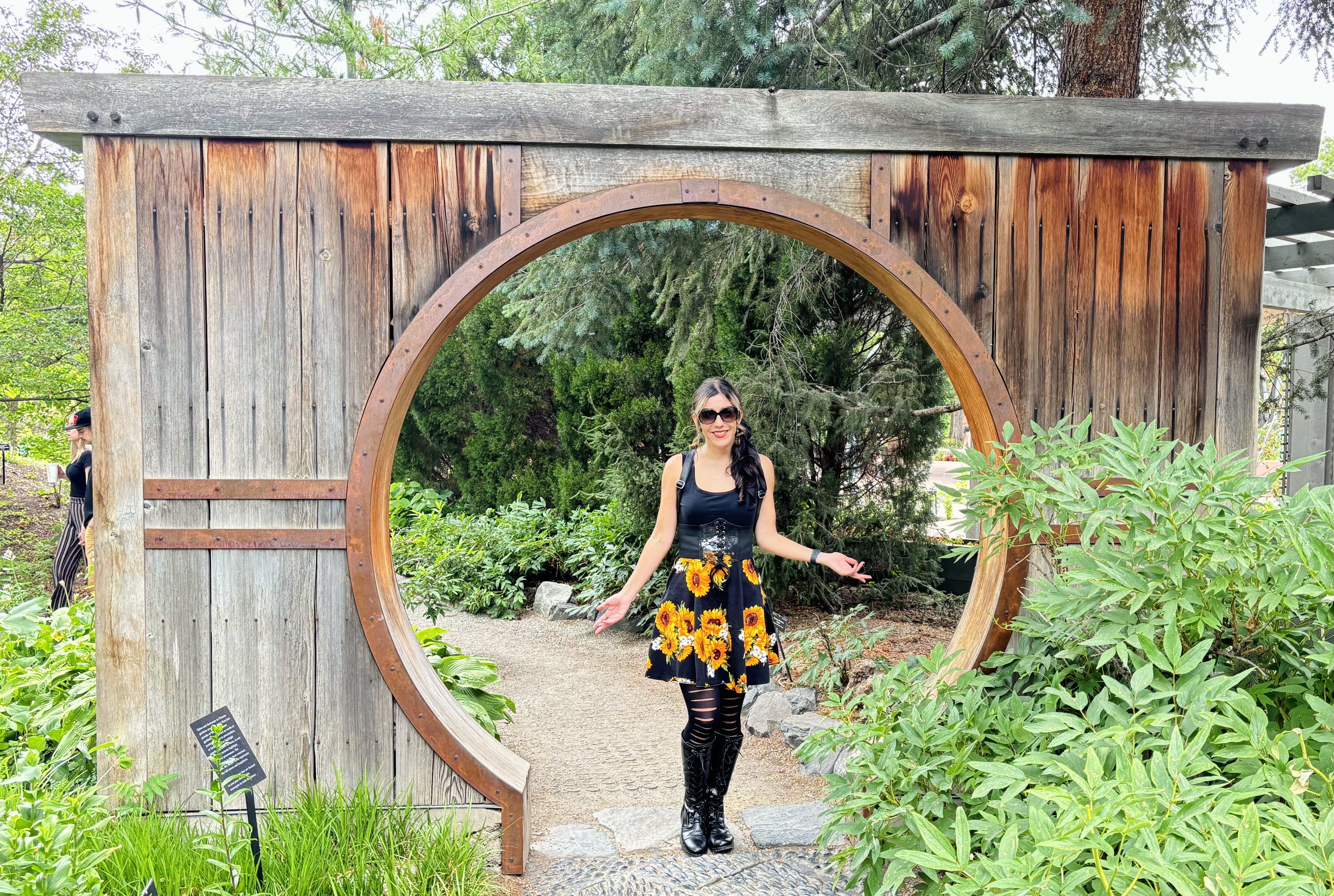 Crysal Mikolaijczak stands in in a wooden garden gateway