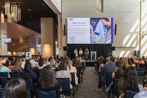 A panel on a stage speaks to a conference audience