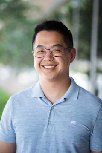 Asian man with black hair wearing glasses and a great polo shirt smiling