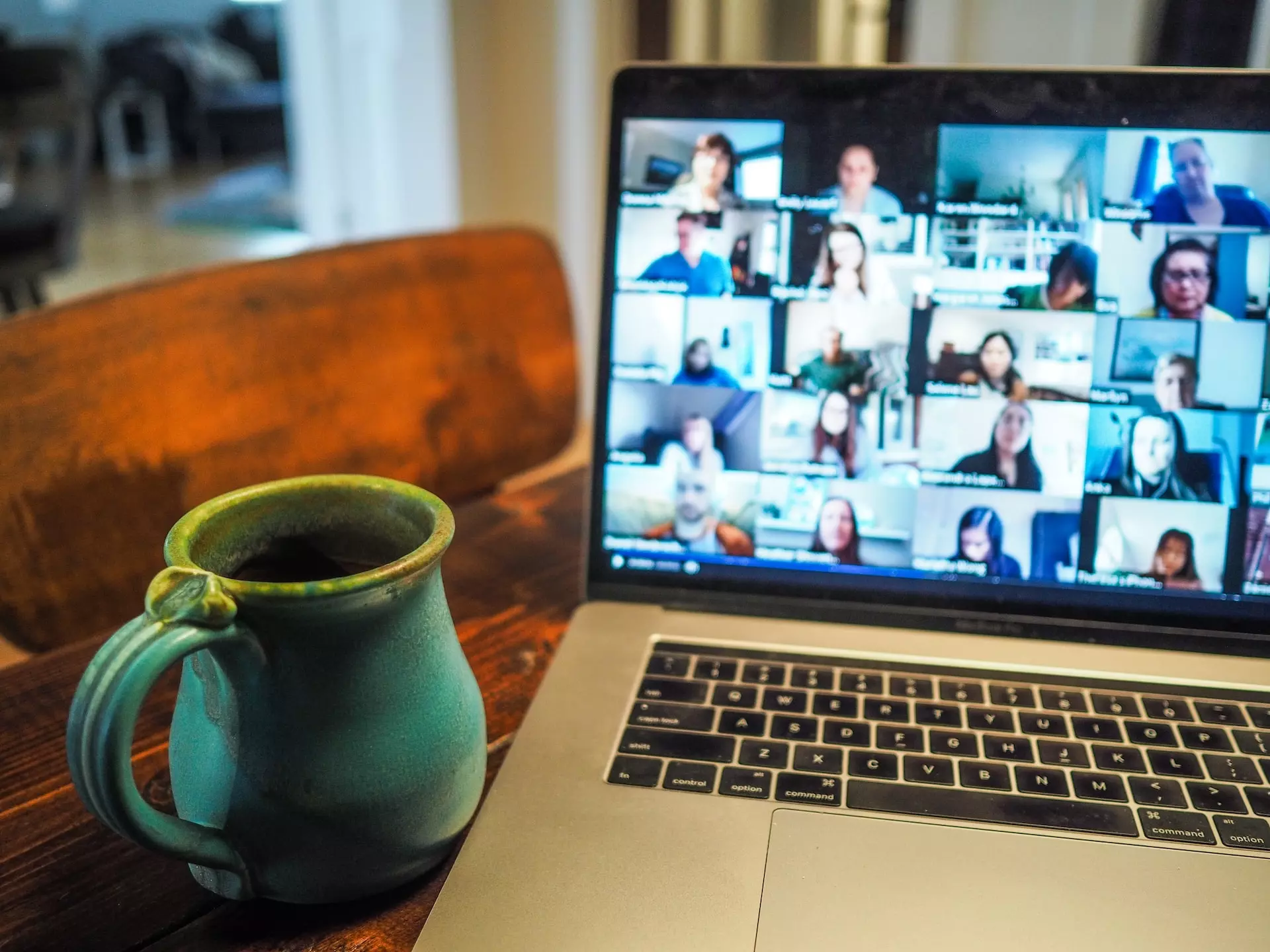 mug next to a laptop with a virtual meeting onscreen and the faces of its participants