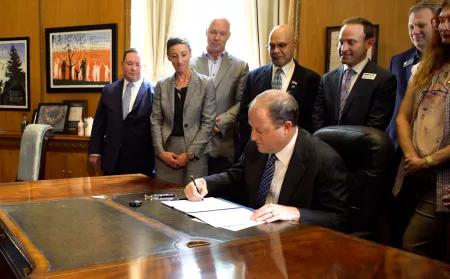 Governor Polis signing a bill in front of OIT staff