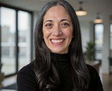 Andrea Day sitting in a black turtleneck smiling. 