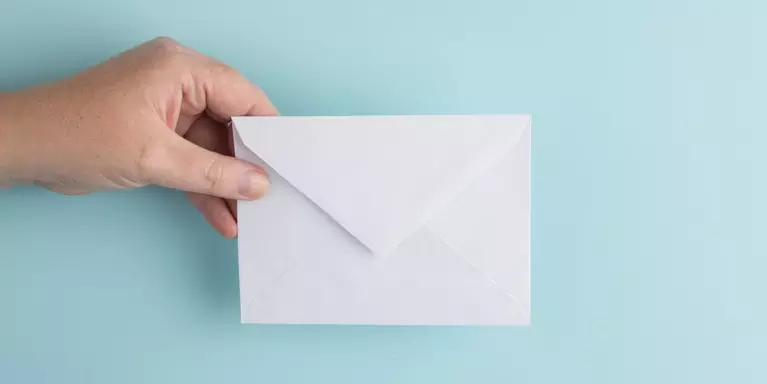 hand holding a white envelope